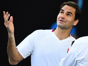 Roger Federer speaks with former tennis player Jim Courier after his victory against Tennys Sandgren in their men's singles quarterfinal match at the Australian Open in Melbourne on Tuesday, Jan. 28, 2020.
