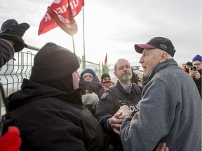 Picketing Unifor members and security guards walk next to a fence erected as part of a blockade which blocked access to the Co-op cardlock location and the Federated Co-operatives Limited (FCL) office on the northeast end of Regina, Saskatchewan on Jan 10, 2020.