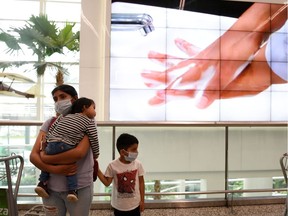 A woman and her son wear protective face masks while standing near a screen showing the hand-washing steps, as part of the security measures due to the outbreak of the coronavirus (COVID-19), at Jose Joaquin de Olmedo International Airport in Guayaquil, Ecuador March 13, 2020. REUTERS/Santiago Arcos
