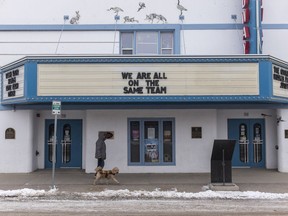 A man walks his dog past the Broadway Theatre.