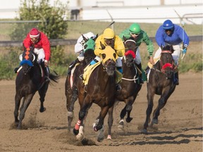 Jockeys race their horses down the track of the second head during the races at Marquis Downs in Saskatoon, Sask. on July 28, 2017.