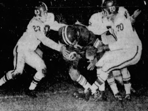 Jack Hill (dark jersey) of the Saskatchewan Roughriders fights for yardage against the Calgary Stampeders in a 1958 Western Interprovincial Football Union game at Taylor Field.