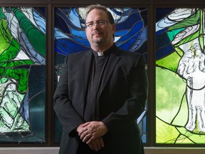 Deacon Eric Gurash stands in front of a stained glass window at the Holy Child Church in Regina, Saskatchewan on May 14, 2020.