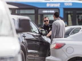 A police officer takes a statement at the Pharmasave on Idylwyld Ave and 33rd St. Police responded to reports of a man being stabbed. Photo taken in Saskatoon, SK on Friday, May 15, 2020.