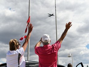 Two people wave to a C-130 Hercules aircraft carrying the Snowbirds demonstration team returning the 15 Wing Moose Jaw on May 25, 2020 after the team repatriated the remains of Capt. Jennifer Casey to Nova Scotia. Casey was killed in a crash in Kamloops on May 17.