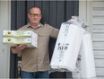 Bryan Baker stands holding meal supplies in front of his home in Regina, Saskatchewan on May 12, 2020. Baker and his wife have been making large batches of meals to give to Carmichael Outreach, where they get distributed to people in need.