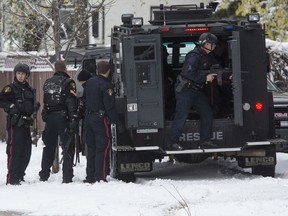 Saskatoon police take cover behind a Bearcat armoured vehicle following an incident involving a barricaded person in the 500 block of Avenue Q North, Oct. 6, 2016.