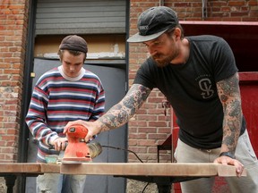 Chef Dale MacKay (right) refinishes tables with his son Ayden (left) outside Ayden Kitchen and Bar in preparation for their reopening on June 23.