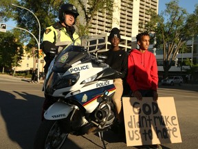 Saskatoon Police Service Staff Sergeant Patrick Barbar lets Holy Cross High School students John-Batist Fimbo and Abraham Makaby take a photo on his motorcycle during the "Black Lives Matter" rally downtown Saskatoon to honour George Floyd and stand up against social injustice. Photo taken in Saskatoon on June 4, 2020.