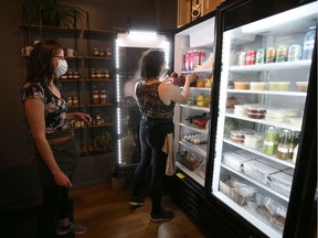 Co-owners Jenna Dube (left) and Taylor Morrison stock the shelves of their new market space at Living Sky Cafe. They added a mini grocery store to their space to meet the demand they hear from their customers who live downtown.