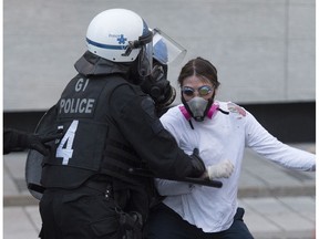 Police push back a protester during a demonstration calling for justice in the death of George Floyd and victims of police brutality in Montreal, Sunday, May 31, 2020.