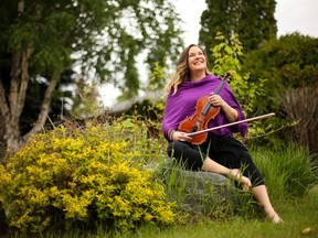 Saskatchewan Fiddle performer and teacher Kim de Laforest sits among the flowers in her backyard in Saskatoon with her fiddle in hand on June 5, 2020.