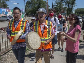 Sherry Brabant, right, holds a photograph of 17 year old Isaiah Brunton, her nephew, as a child, who was shot and killed in Pleasant Hill on Feb. 15, 2020, as Drummers lead a smudge walk on 22nd Street West in Saskatoon on July 11, 2020.