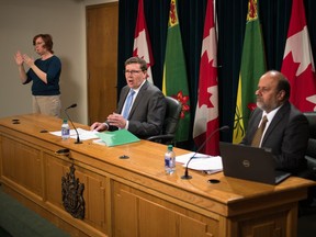 Saskatchewan Premier Scott Moe, centre, speaks at a news conference held at the Saskatchewan Legislative Building in Regina, Saskatchewan on April 23, 2020. On Moe's left is sign language interpreter Karen Nurkowski and on his right is Saskatchewan's chief medical health officer Dr. Saqib Shahab.