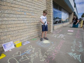 William Stene looks over messages in chalk on the sidewalk outside Minister of Education Gord Wyant's office. Parents affiliated with the organization Keep Saskatchewan Kids Safe invited people to write messages outside of the minister's office in Saskatoon, SK on Wednesday, August 26, 2020.