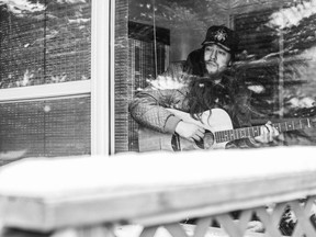 Musician Forrest Eaglespeaker plays guitar in his porch.