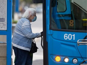 A woman wears a mask as she boards a city bus downtown in downtown Saskatoon.