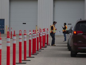 Health care workers wait outside for patients at a drive-thru testing site in Saskatoon, Saturday, September, 12, 2020.