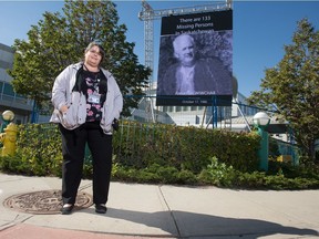 Rhonda Fiddler, missing persons liaison with the Regina Police Service Victim Services Unit, stands next to a new electric billboard displaying missing persons in front of the new police headquarters building on Saskatchewan Drive in Regina, Saskatchewan on Sept. 16, 2020.