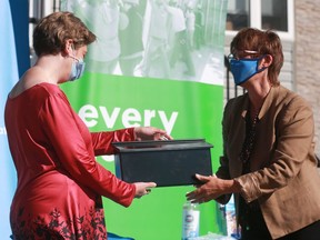 Anita Burzinski accepts a mailbox from Habitat for Humanity Saskatoon CEO Brenda Wallace during a ceremony welcoming families into their new Habitat for Humanity homes.