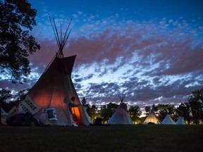 Teepees stand together at the Justice for our Stolen Children camp across from the Saskatchewan legislative building as summer daylight slowly gives way to a night sky over Regina.