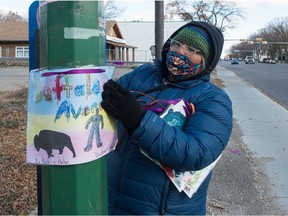 Joely BigEagle-Kequahtooway hangs a piece of art submitted by students of Prairie Sky School, as part of the Buffalo Avenue Art Action event on Dewdney Avenue in Regina, Saskatchewan on Oct. 17, 2020. The event saw buffalo-inspired artwork submitted by community members displayed along Dewdney Avenue to raise awareness about the calls to change the street's name to Buffalo Avenue.