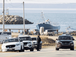 RCMP officers monitor the entrance to Saulnierville Harbour while in the background another checkpoint is being maintained, as non-Indigenous commercial fishermen protest against a Mi'kmaq lobster fishery in Nova Scotia, October 19, 2020.