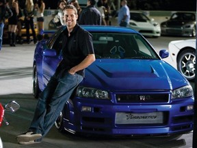 PAUL WALKER as agent Brian O'Conner leans against his 1998 Nissan Skyline GTR in the ultimate chapter of the franchise built on speed--"Fast Furious".