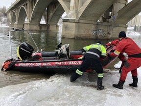 Members of the Saskatoon Fire Department retrieve a rescue boat used to says save a woman on an ice shelf on the South Saskatchewan River.