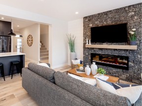 Fireplaces are often a gathering point in a living space. The dark real stone fireplace surround contrasting with the white shiplap create a stylish gathering spot in this Pure Developments show home.