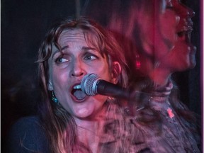 Dara Schindelka is seen behind plexiglass at a concert at Somewhere Else Pub in Saskatoon, with singer Stacey Springal in the background.