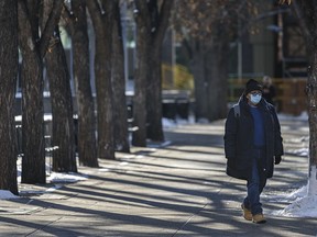 A masked pedestrian walks in downtown Calgary on Friday, Nov. 20, 2020. For the second day in a row, COVID-19 cases hit record highs in Alberta on Friday.