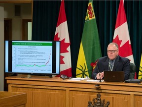 Saskatchewan Health Authority CEO Scott Livingstone sits next to a television displaying a presentation during a news conference regarding COVID-19 at the Saskatchewan Legislative Building in Regina, Saskatchewan on Nov. 26, 2020.