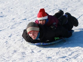 Donny Larmour sleds down a hill at Harold Tatler Park South with his daughter Jane on his back.