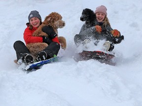 Isabella Duncan, left and Talia Nicholson have fun sledding with their dogs Tucker and Birdie in Confederation Park after an overnight snowstorm hit Calgary on Tuesday, Dec. 22, 2020. After we conquer the pandemic, it will be time to rethink community and society, says columnist.
