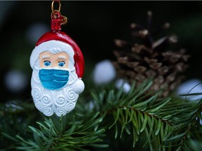 This picture taken in Paris on December 22, 2020 shows a Christmas Santa Claus decoration, with a protective mask.