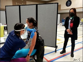 Asagewin Carriere vaccinates Vanessa Carr as Lac La Ronge Indian Band Chief Tammy Cook-Searson looks on. Photo provided by Jim Searson on Jan. 12, 2021. (Saskatoon StarPhoenix).