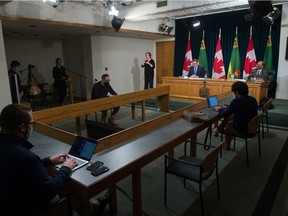 Saskatchewan Premier Scott Moe, left at desk in the back of the room, and Saskatchewan's chief medical health officer Dr. Saqib Shahab, right at desk, speak to media during a news conference, regarding COVID-19, held at the Saskatchewan Legislative Building in Regina, Saskatchewan on Jan. 19, 2021.