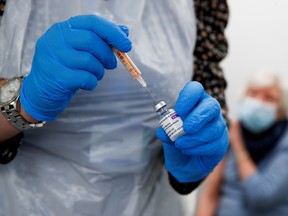A health worker fills a syringe with a dose of the Oxford/AstraZeneca COVID-19 vaccine at the Appleton Village Pharmacy in Widnes, Britain, January 14, 2021.