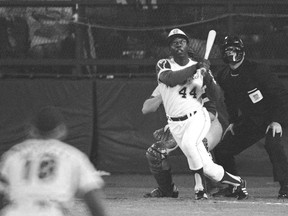 Atlanta Braves' Hank Aaron eyes the flight of the ball after hitting his record-setting 715th career homer in a Major League Baseball game against the Los Angeles Dodgers on April 8, 1974. Dodgers pitcher Al Downing and umpire David Davidson look on. Aaron died Friday at 86.