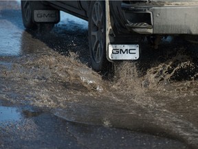 A vehicle drives through a puddle on McDonald Street in Regina, Saskatchewan on Mar. 4, 2021. Temperatures rose above freezing Thursday, with even warmer temperatures expected throughout the coming weekend.