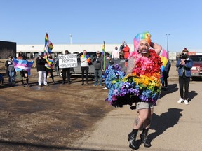 Regina-based drag performer Katy Hairy dances and lip syncs to a song in front of Regina Victory Church in Regina, Sask. as part of a rally against a sermon posted online by the church's pastor, while Craig MacMillan tries to photo-bomb the performance with his sign about forgiveness on March 14, 2021.