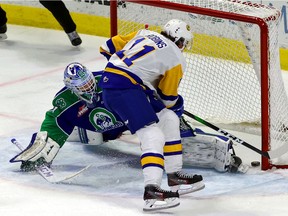 Swift Current Broncos vs. Saskatoon Blades on March 24, 2021 at the Brandt Centre. Saskatoon's Tristen Robins scores in overtime against Broncos goalie Isaac Poulter. Keith Hershmiller Photography.