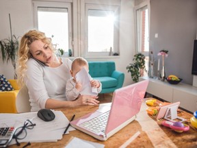 Worried mother holding baby and talking on smart phone at home office