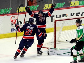The Regina Pats' Braxton Whitehead, with his arms in the air, celebrates his first WHL goal with teammate Cole Carrier on Thursday against the Prince Albert Raiders at the Brandt Centre.