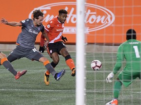 Cavalry FC forward Dominique Malonga shoots the ball past Forge FC defender Klaidi Cela in the second half of a 2019 Canadian Premier League soccer match at Tim Hortons Field in Hamilton.
