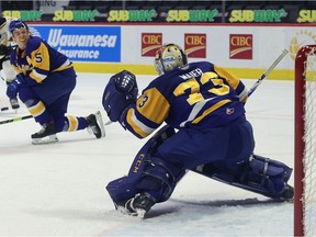 Saskatoon Blades goalie Nolan Maier (73) prepares to stop a shot by the Brandon Wheat Kings' Vincent Iorio (14) while Saskatoon's Aidan De La Gorgendiere (5) looks on April 11, 2021 at the Brandt Centre. Keith Hershmiller Photography.