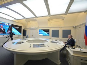 Russian President Vladimir Putin (R) attends a video conference meeting as US President Joe Biden is seen on  screen, as part of the virtual US-hosted Leaders Summit on Climate, in his residence in Moscow, on April 22, 2020.