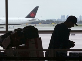 A passenger waits beside their luggage at the departure terminal at Toronto Pearson Airport, in Mississauga, Ont., Friday, May 24, 2019.