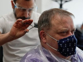 Chris, owner of Stag Co barbers, cuts hair as hairdresser shops reopen, as the coronavirus disease (COVID-19) restrictions ease, in Herford, Britain April 12, 2021.